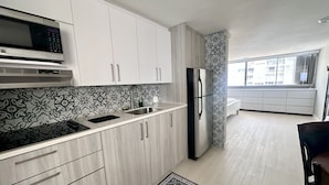 A modern kitchen with white cabinets, a microwave, a sink, and a refrigerator. - Beach front, best location, ocean and city views + parking! (San Juan)