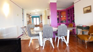 A dining area with a table and chairs, a kitchen in the background, and a bookshelf with books. - Spacious Apartment in Evian with Lake View, Balcony, and Pet-Friendly (Évian-les-Bains)