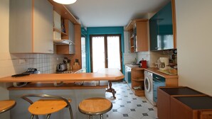 A compact kitchen with a central island, bar stools, a washing machine, and a sink. - Spacious Apartment in Evian with Lake View, Balcony, and Pet-Friendly (Évian-les-Bains)