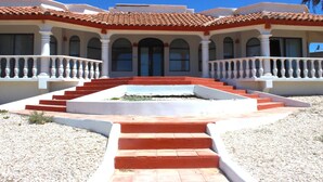 A building with a red-tiled roof, white columns, and a central staircase leading to the entrance.