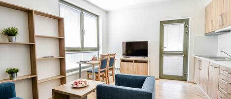 A compact living space with a dining area, a TV, and a kitchenette.