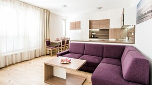 Una sala moderna con un sofá morado, una mesa de centro de madera y un comedor con sillas y una mesa.
