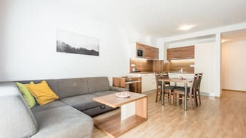 Una sala de estar moderna con un sofá gris, una mesita de centro de madera y un comedor con una mesa y sillas de madera.