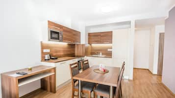 A modern kitchen with wooden cabinets, a built-in microwave, and a dining area with a wooden table and chairs.