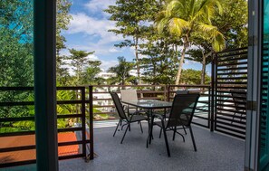 An outdoor patio with a table and chairs, surrounded by a metal fence and palm trees. - ★ Happy Turtle Loft - Sparkling clean corner loft steps to Sandy Beach ★ (Rincon)