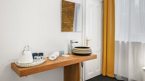 Een badkamer met een houten wastafel, een witte waterkoker, een kom en een handdoek.