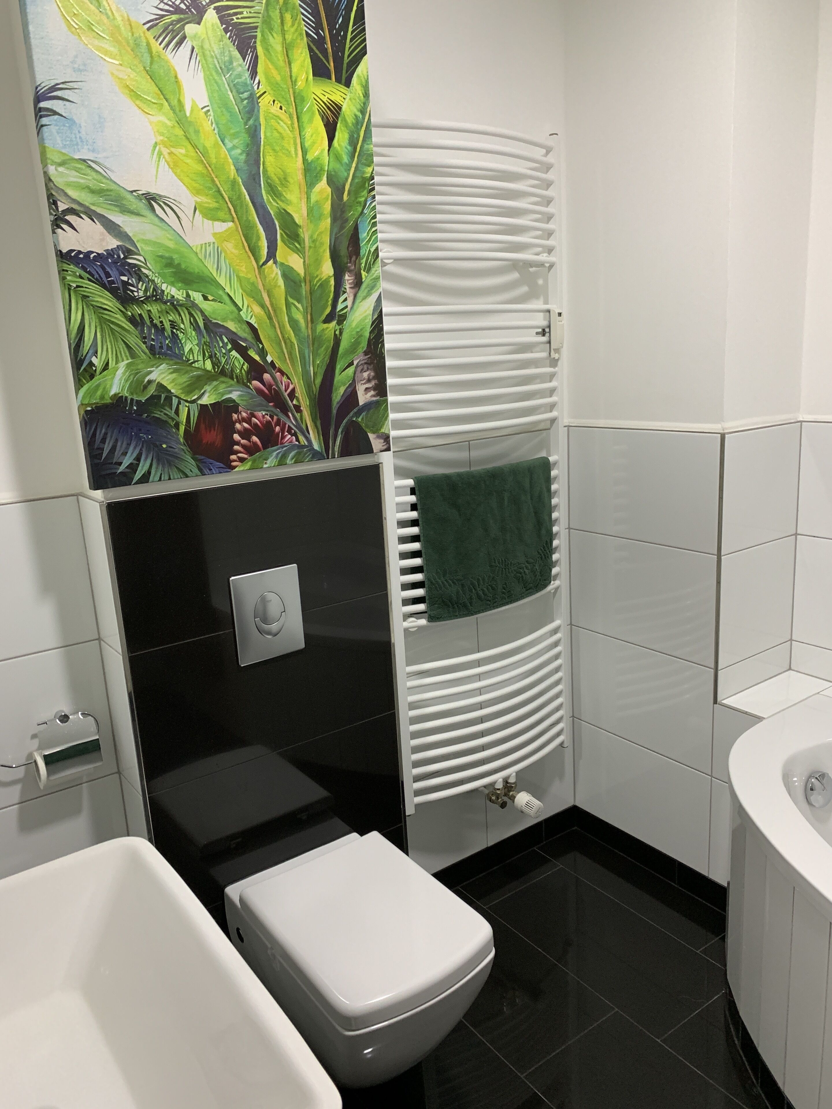 Ein Badezimmer mit Toilette, Waschbecken und Badewanne. Ein Handtuchhalter mit einem grünen Handtuch.