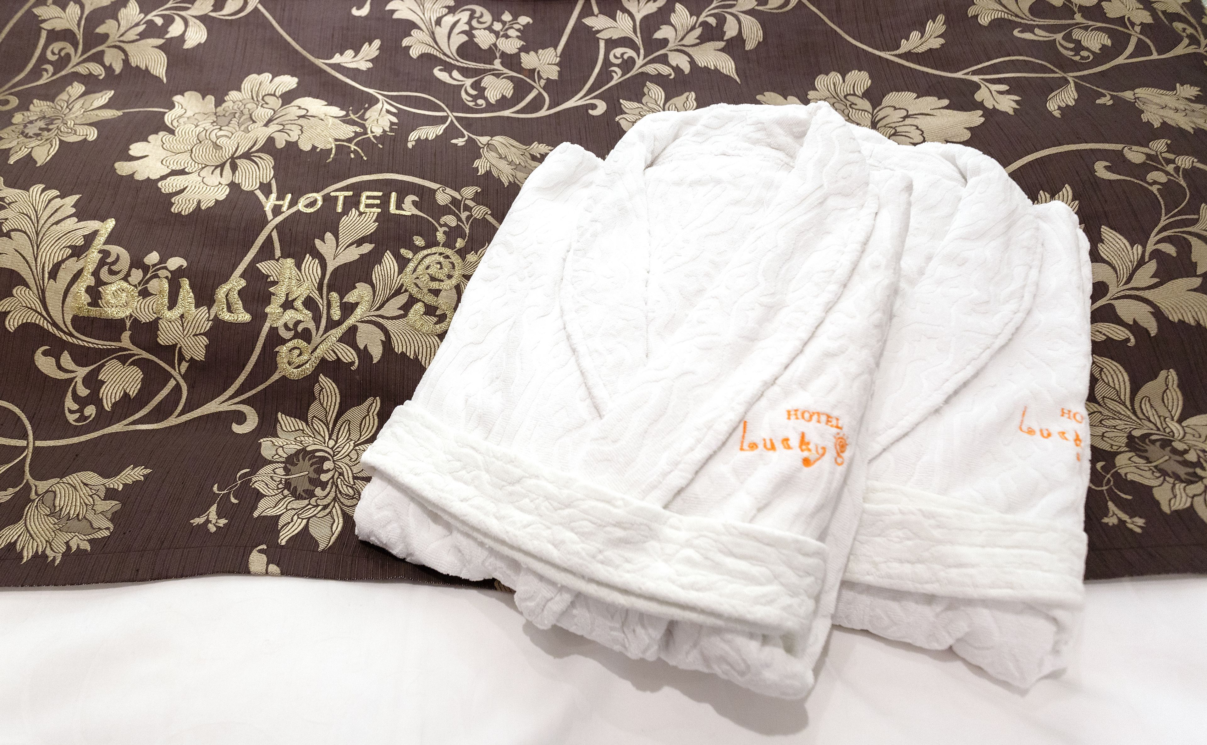 Un albornoz blanco doblado cuidadosamente sobre una cama con cabecera de estampado floral.