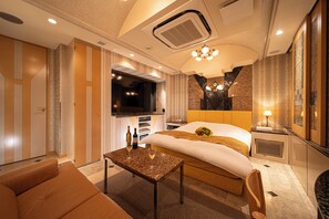 Quarto de hotel com cama, televisão, mesa com copos e sofá.