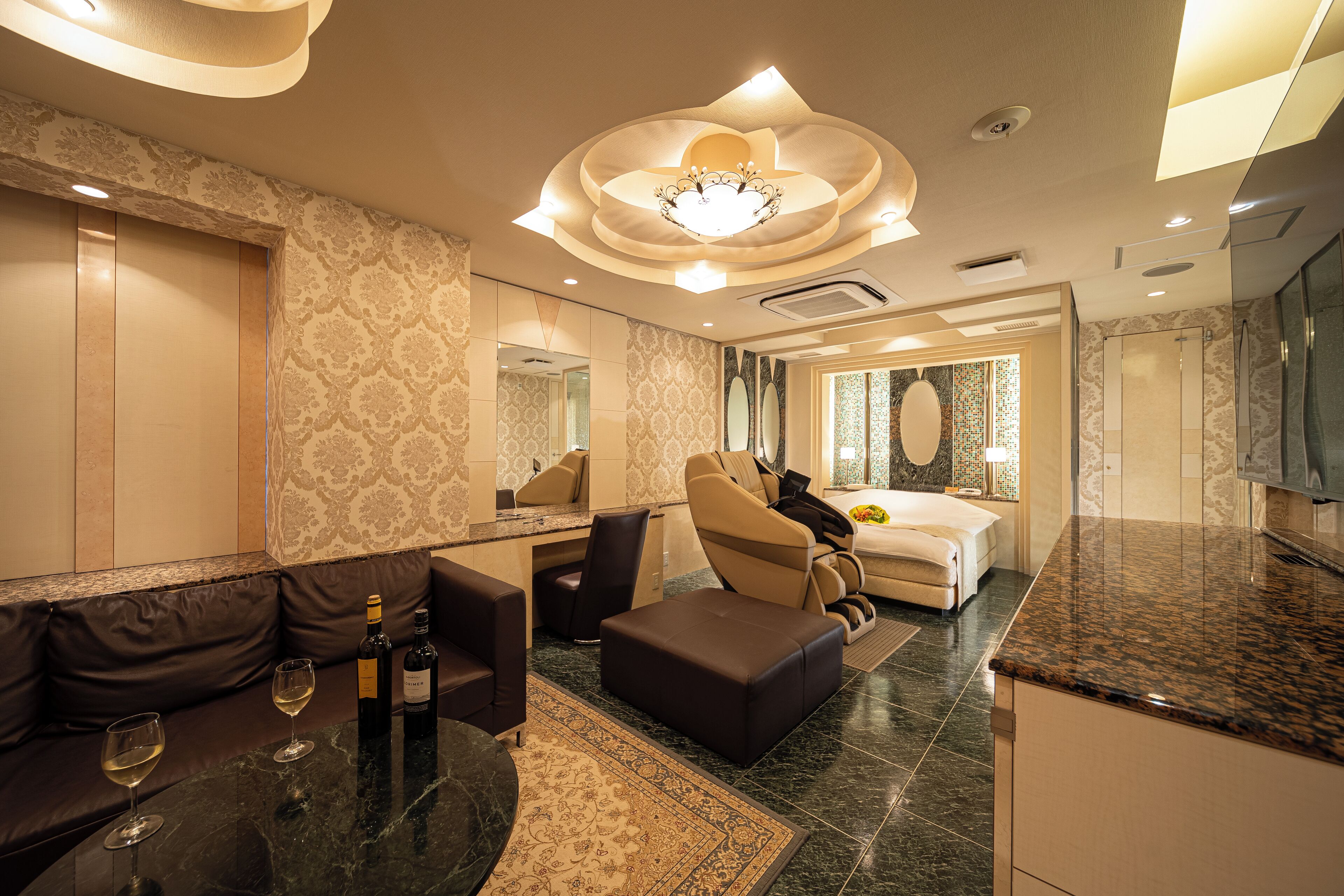 A modern hotel room with a sofa, ottoman, and a dining area.