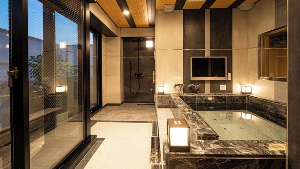A modern bathroom with a glass-enclosed shower, a marble bathtub, and a large mirror. - Lucky Sun (Nishinomiya)