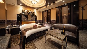 A hotel room with a bed, a seating area, a table with wine bottles, and a coat rack. - Lucky Sun (Nishinomiya)