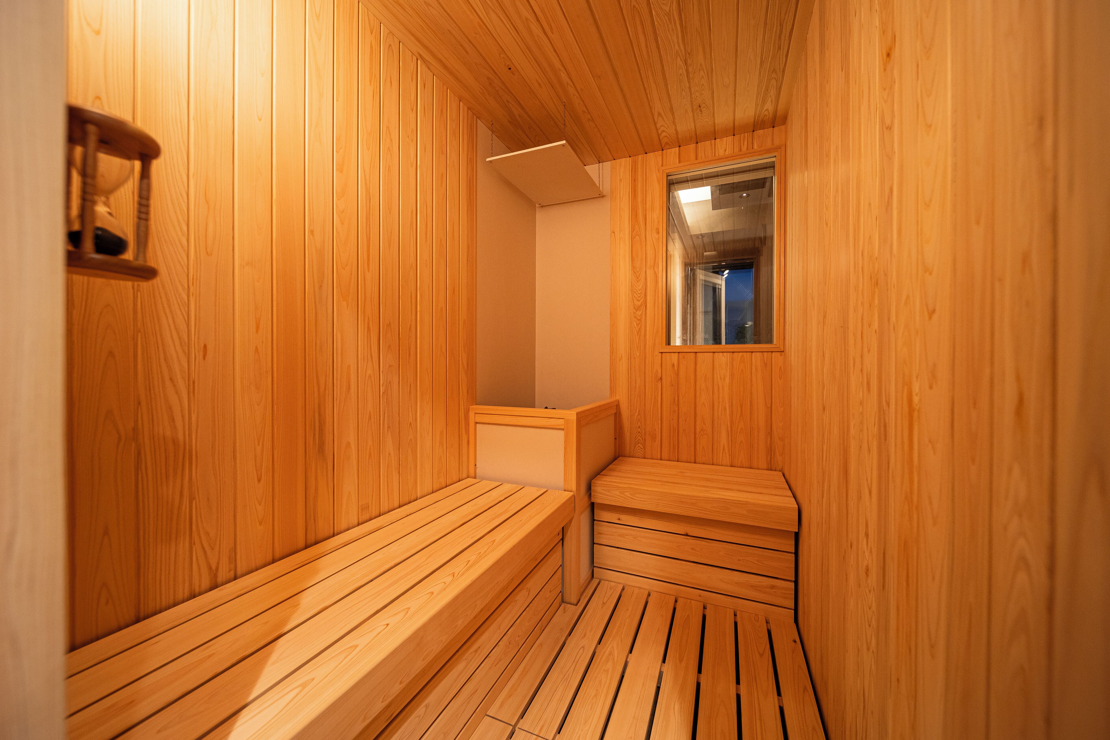 Una sauna de madera con bancos y un ventanal pequeño.