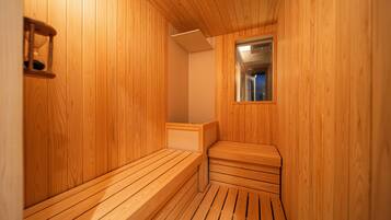 Una sauna de madera con bancos y un ventanal pequeño.