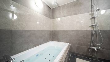A modern bathroom with a bathtub, shower, and a ceiling light fixture.