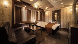 A hotel room with a bed, a sofa, a small table with a bottle and glass, and a minibar. - Lucky Sun (Nishinomiya)