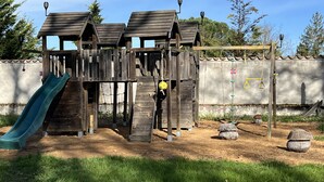 A wooden play structure with a slide and climbing elements. - The Orangery of Chatel for 6, 2019 Figaro Magazine cover heated swimming poll (Cleppé)
