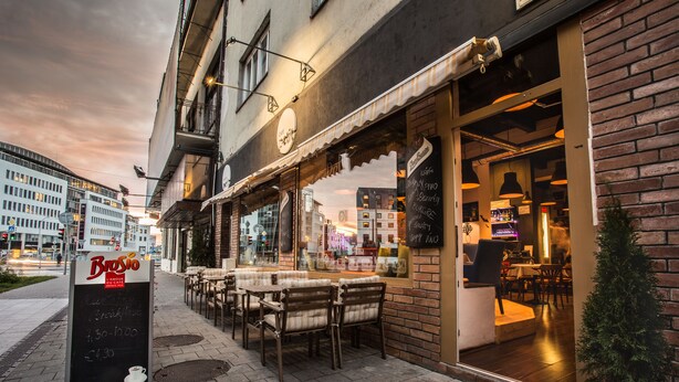 Un restaurante con terraza, un menú en pizarrón y vistas a la ciudad.
