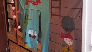 A bunk bed with a wooden frame, a hanging curtain with a pirate-themed design, and a wall mural of a pirate character.