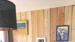 A blue wooden cabinet with drawers, a hanging lamp, and framed artwork on a wooden wall.