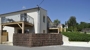 A modern two-story house with a balcony, a wooden fence, and a well-maintained hedge. - Studio comfort in the heart of Jonzac (jonzac)