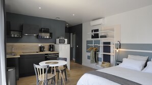 A compact hotel room with a kitchenette, a dining area, and a bed. - Studio comfort in the heart of Jonzac (jonzac)