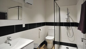 A modern bathroom with a white sink, toilet, and shower. - Studio comfort in the heart of Jonzac (jonzac)