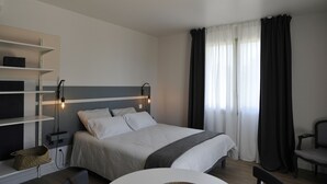 A modern hotel room with a bed, bedside tables, a chair, and a desk. - Studio comfort in the heart of Jonzac (jonzac)