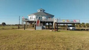 A single-story building with a central tower, a covered deck area, and a fenced perimeter. - Centurion: 3  BR, 2  BA House in Caplen, Sleeps 10 (Bolivar Peninsula)