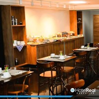 Um espaço de refeições de hotel com painéis de madeira, um serviço de buffet e várias mesas e cadeiras.