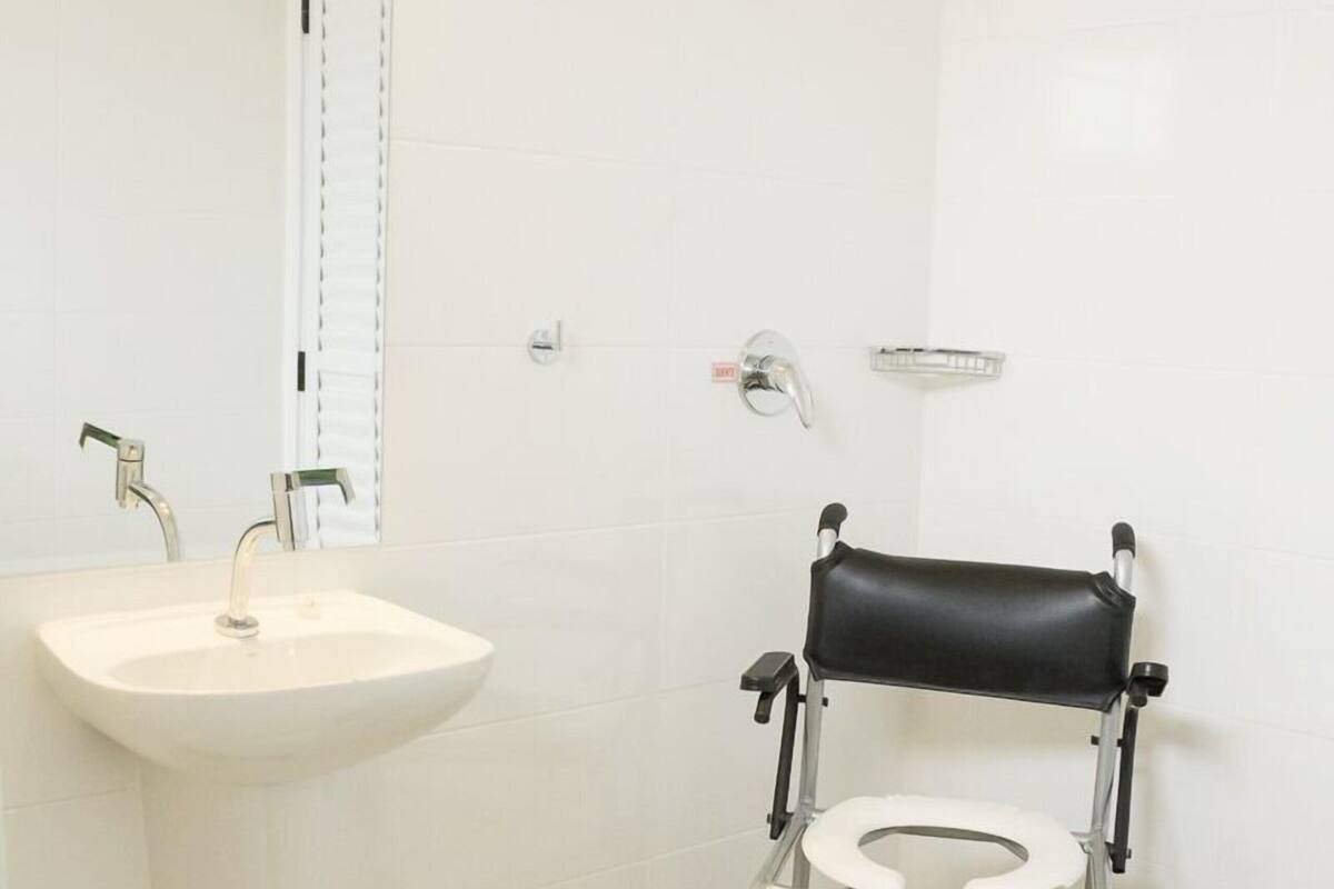 A bathroom with a white sink, a shower, and a wheelchair-accessible toilet.