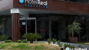 A HotelReal Executive building with a modern glass facade, a prominent logo, and a signboard above the entrance.