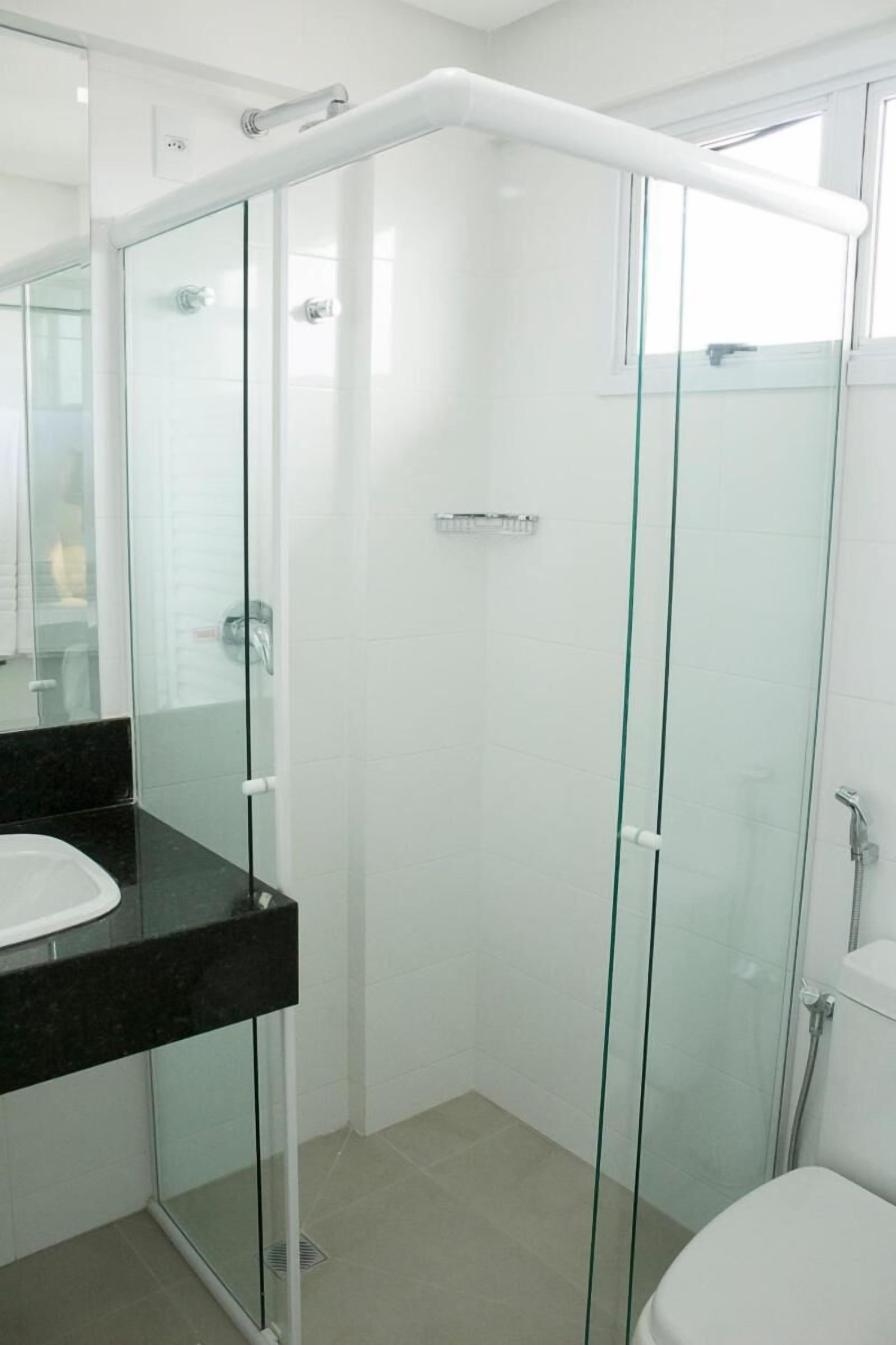 Un baño moderno con ducha envuelta en vidrio, encimera negra y inodoro blanco.