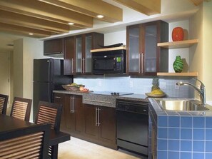Une cuisine moderne avec des meubles de rangement en bois foncé, un micro-ondes noir et un évier en acier inoxydable.