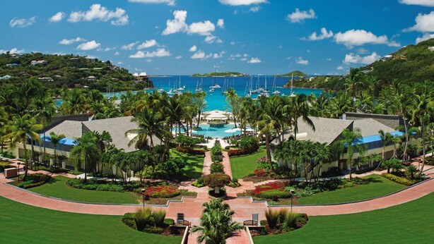 Un resort con piscina central, rodeado de palmeras y vistas al océano.