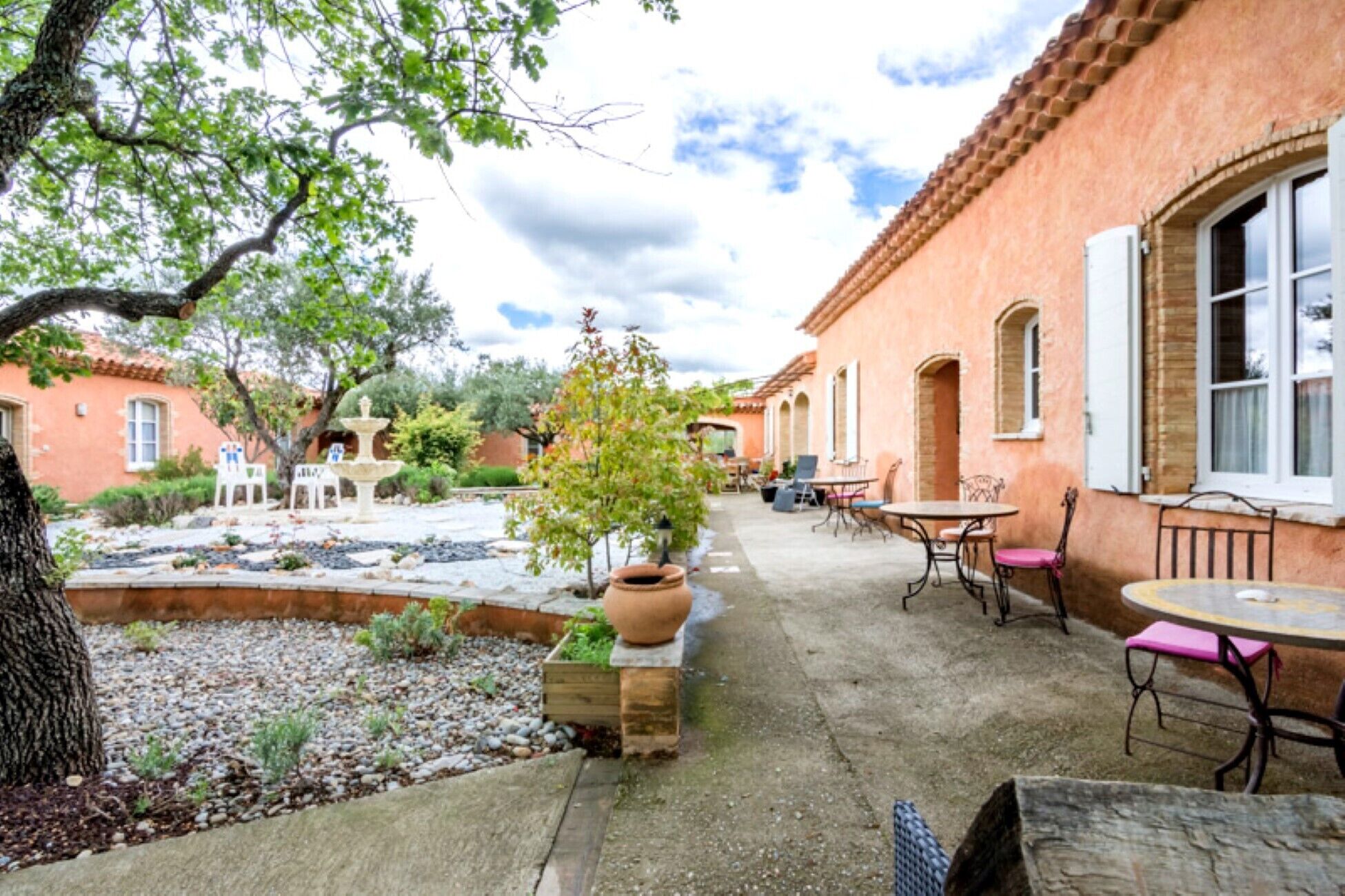 Un cortile con una fontana, posti a sedere all'aperto e un edificio con finestre ad arco.