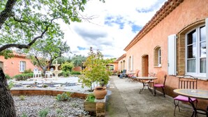 A courtyard with a fountain, outdoor seating, and a building with arched windows. - Apartment "Bleu Provence" (Les Salles-sur-Verdon)