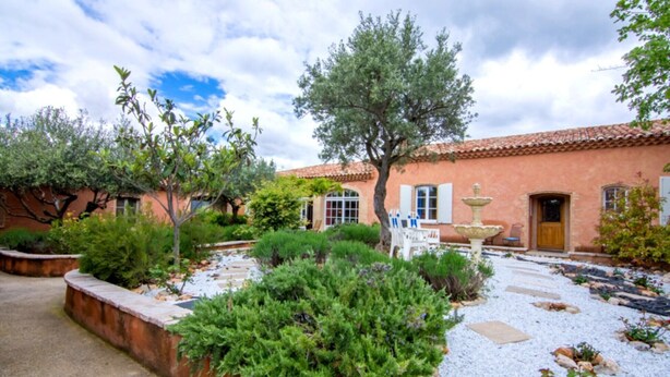 A courtyard with a fountain, a building with a tiled roof, and various plants. - Apartment "Bleu Provence" (Les Salles-sur-Verdon)