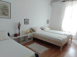 A bedroom with two single beds, a bedside table with a lamp, a small potted plant, and a framed picture on the wall.