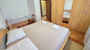 A bedroom with a bed, a wooden wardrobe, a chair, and a small table. - Holiday apartment with terrace and air conditioning (Novi Vinodolski)