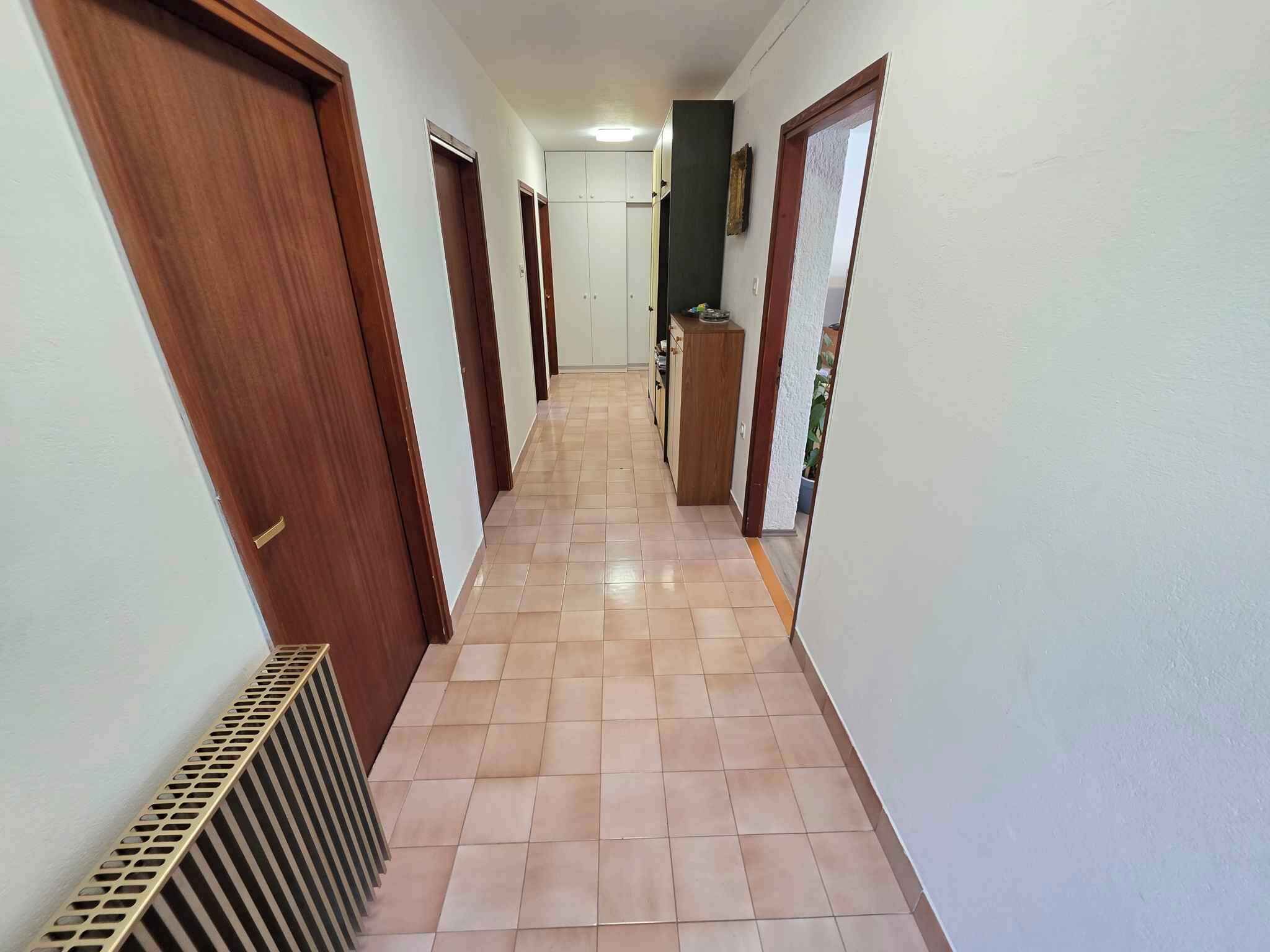 A hallway with wooden doors, a radiator, and a tiled floor.