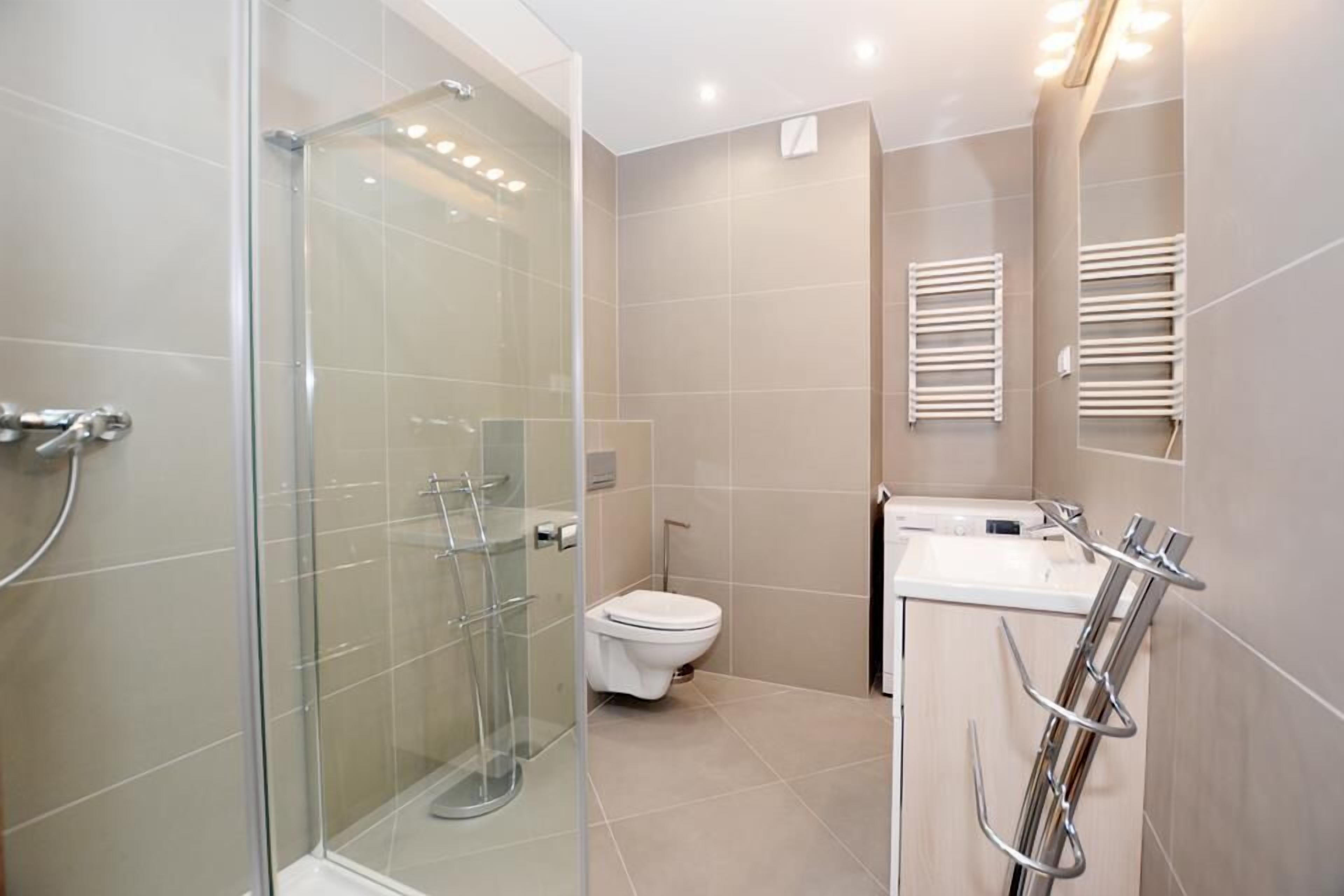 Een moderne badkamer met een douchecabine, toilet en wastafel met handdoekhouder.