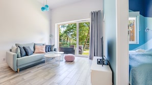 A modern living room with a sofa, coffee table, and a view of the outdoors. - Apartamenty Sun & Snow Dwie Sosny (Ustronie Morskie)