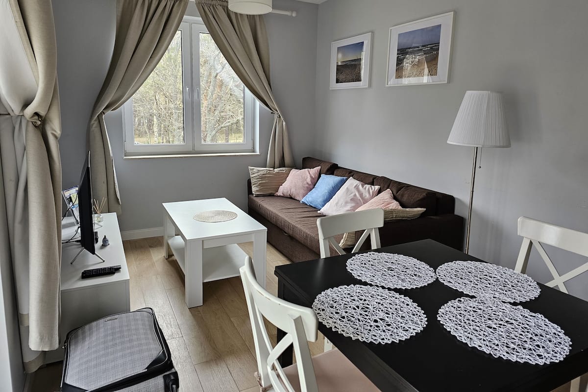 Un espace de vie compact comprenant un canapé, une petite table, une chaise, un téléviseur et une lampe.