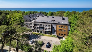 A modern multi-story building with a parking lot and a view of the sea. - Apartamenty Sun & Snow Dwie Sosny (Ustronie Morskie)
