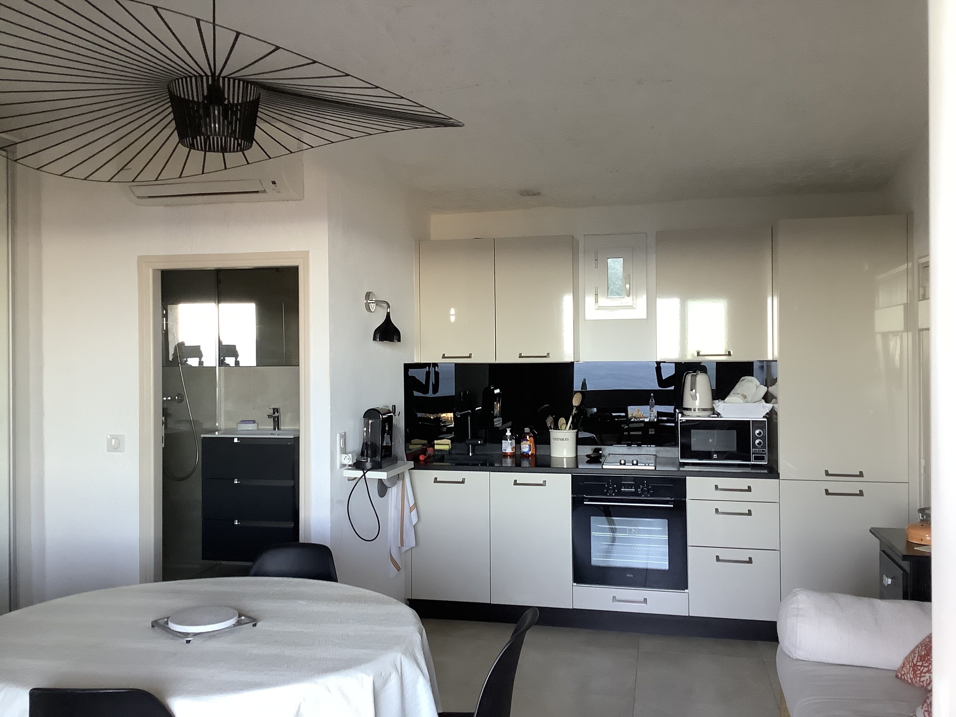 Una cocina moderna con armarios blancos, una mesa de comedor y un lámpara en el techo.
