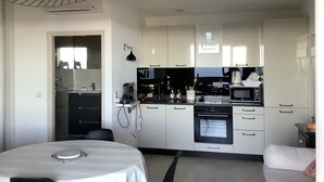 A modern kitchen with white cabinets, a dining table, and a ceiling light fixture.