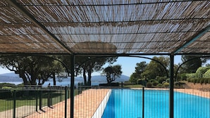 A covered outdoor area with a swimming pool, a table, and chairs.