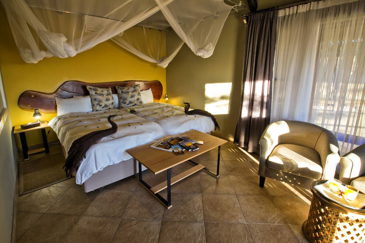 A bedroom with a bed, a bedside table, a chair, and a small table.