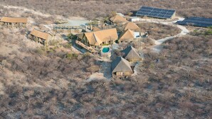 An aerial view of a resort with multiple buildings, a swimming pool, and solar panels. - Safarihoek (Kamanjab)